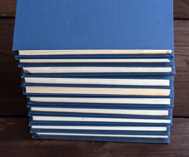 büyük bir mavi kapak kitaplarında kahverengi ahşap bir masa üstten görünüm üzerinde yığını