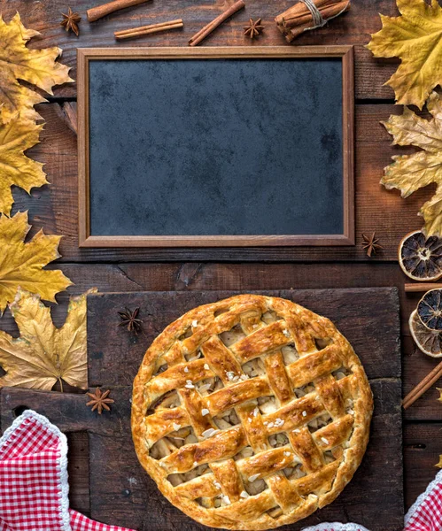 empty black chalk board and baked whole fruit cake on brown wooden background, apple pie recipe