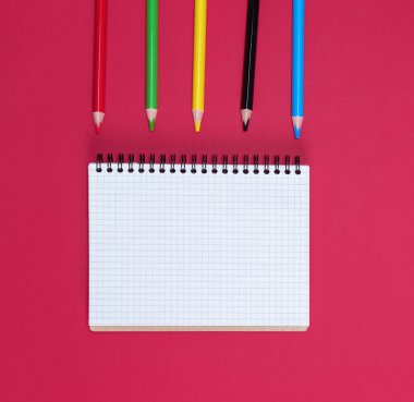 Boş beyaz çarşaflar ve çok renkli tahta kalemlerle açık bir defter.