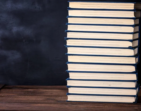 大叠的书籍在一个蓝色的封面上的棕色木桌上 复制空间 — 图库照片