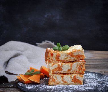 kare parçalar ile siyah kesme tahtası üzerinde kabak cheesecake