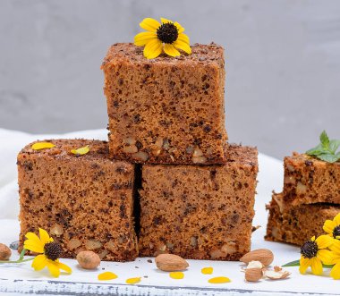 kare bir pasta grafiğin dilimlerini whith fındık bir beyaz tahta masa, sünger kek pişmiş