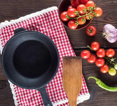 boş siyah tava ve taze olgun kırmızı kiraz domatesleri dallarda.