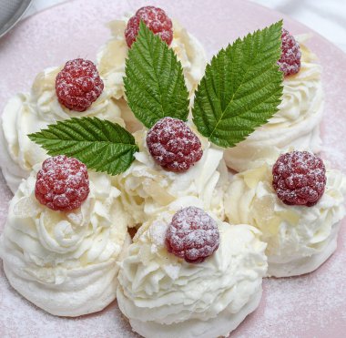 pişmiş kek yumurta beyazı yaptı ve pembe tabağa Pavlova tatlı ahududu ile beyaz krem şanti