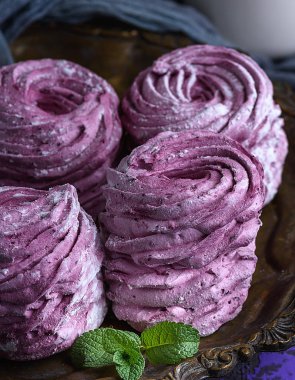 Bakır bir tabakta duran pudra şekeriyle serpilmiş büyük pembe marşmelov.