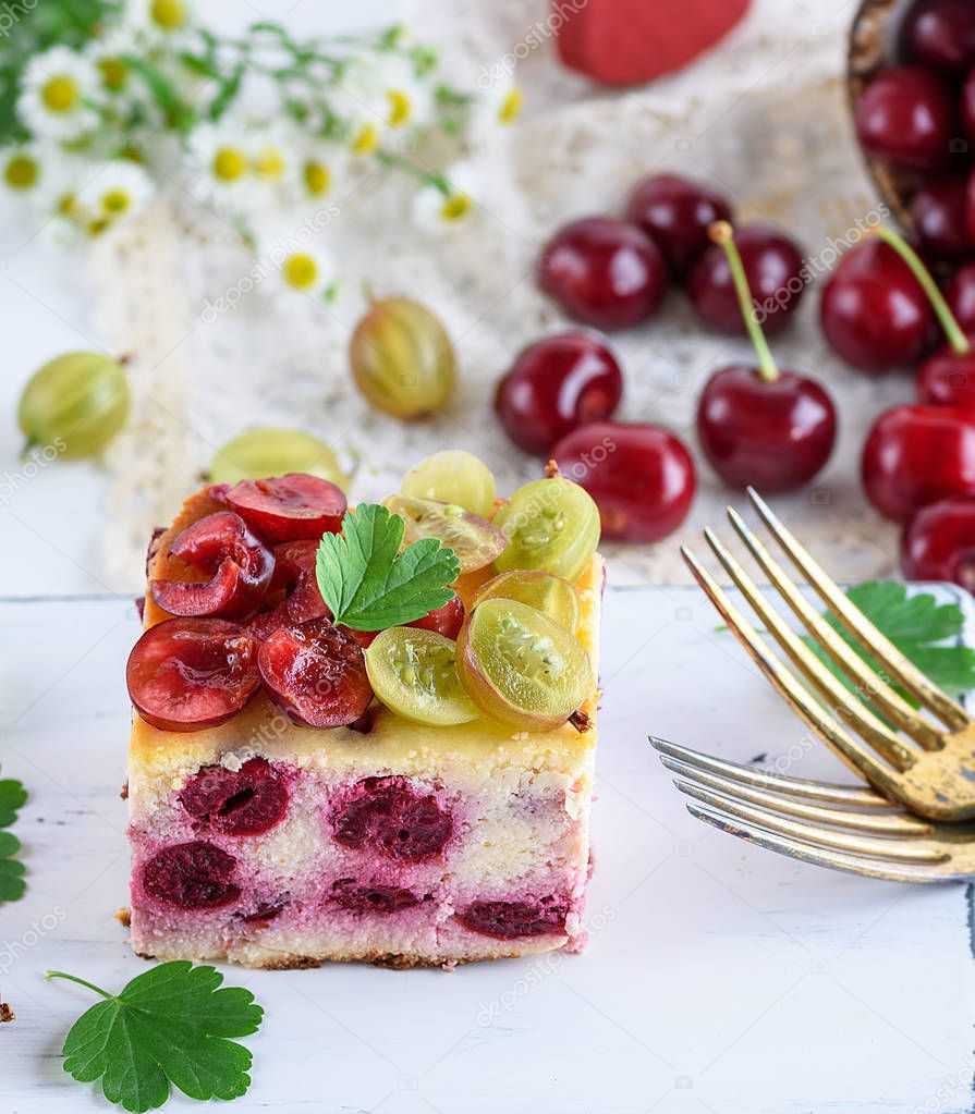 cheesecake with cherry berries and homemade cottage cheese, decorated with gooseberry on a white wooden board and two forks