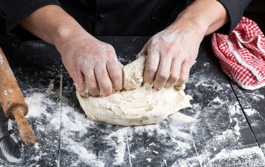 aşçı beyaz buğday unu hamur siyah ahşap bir masa üzerinde kneads
