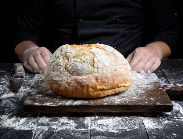 yuvarlak bir eski kahverengi ahşap tahta ve Şef eller ev yapımı ekmek