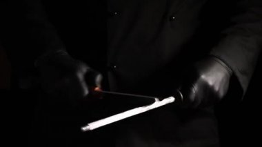 Siyah lateks eldiven aşçı bir bıçak üzerinde ahşap bir masa keskinleştirir.