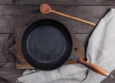 boş siyah yuvarlak ahşap sapı ve kahverengi bir tabloda, üstten görünüm tahta kaşık ile pan