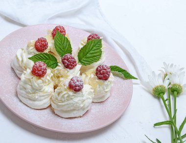 pişmiş kek yumurta beyazı yaptı ve pembe tabağa Pavlova tatlı ahududu ile beyaz krem şanti