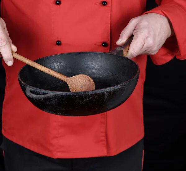 Cozinhar Uniforme Vermelho Segurando Uma Frigideira Preta Vazia Fundo Preto — Fotografia de Stock