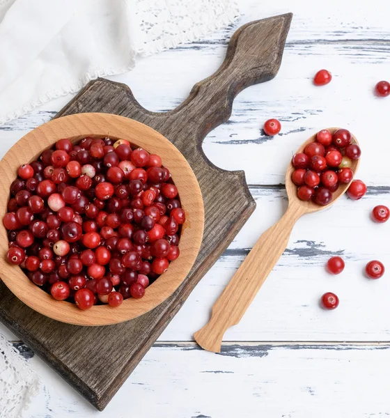 Olgun lingonberries beyaz bir tabloda, üstten görünüm ahşap bir kase kırmızı meyveler