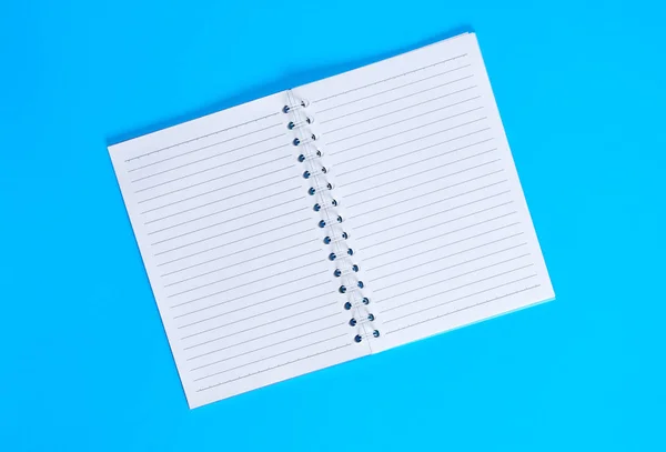 笔记本 线条中的白色纸张为空 背景为蓝色 顶部视图 — 图库照片