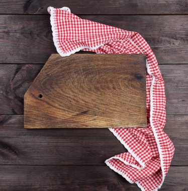 Boş çok eski ahşap mutfak kesme tahtası ve kırmızı havlu kahverengi bir tabloda, üstten görünüm