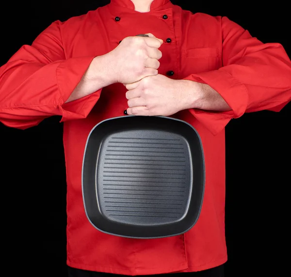 Cozinhe Uniforme Vermelho Segurando Uma Frigideira Preta Quadrada Vazia Fundo — Fotografia de Stock