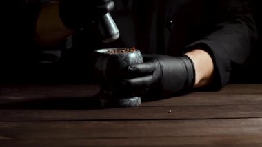 Siyah lateks eldiven Şef pişirme ve baharatlar, ağır çekim taşlama biber, karışımı ile taş harç tutar