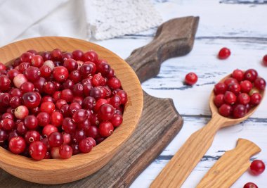 Olgun lingonberries beyaz bir tabloda, üstten görünüm ahşap bir kase kırmızı meyveler