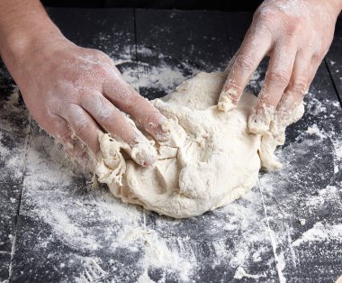 Baker beyaz buğday unu hamur siyah ahşap bir masa üstten görünüm üzerinde kneads