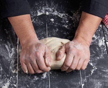 Baker beyaz buğday unu hamur siyah ahşap bir masa üstten görünüm üzerinde kneads