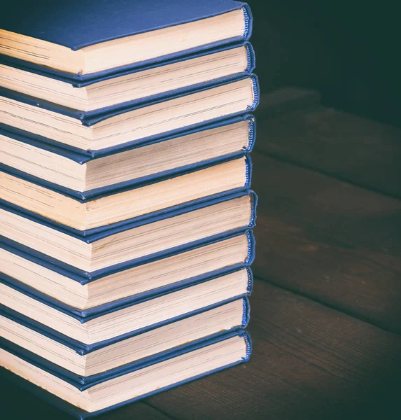 茶色の木製のテーブルの上の青いカバーの本の山 — ストック写真