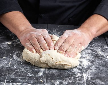 Baker beyaz buğday unu hamur siyah ahşap bir masa üstten görünüm üzerinde kneads