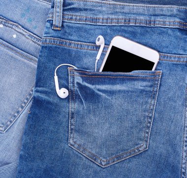 Kot pantolonun arka cebinde kulaklık olan beyaz akıllı telefon.