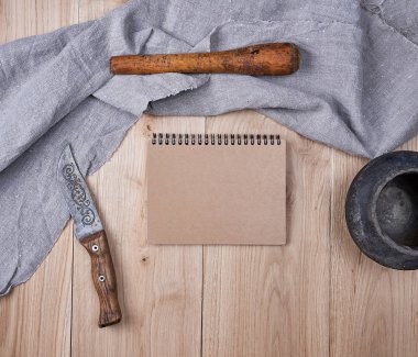 açık kahverengi sayfalarıyla birlikte boş dizüstü bilgisayar ve bir mutfak bıçağı masaya, üstten görünüm