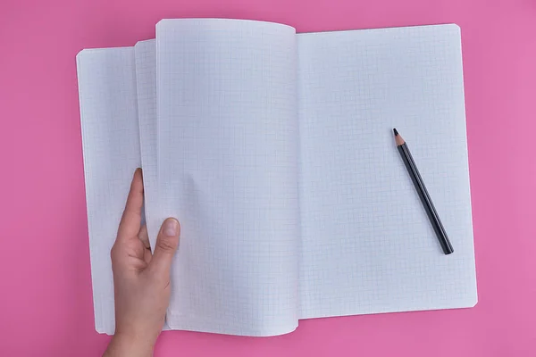 Cuaderno Abierto Vacío Una Celda Una Mano Femenina Fondo Rosa — Foto de Stock