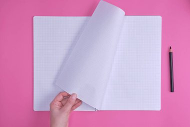 boş açık defter bir hücre ve bir el, pembe bir arka plan, üstten görünüm