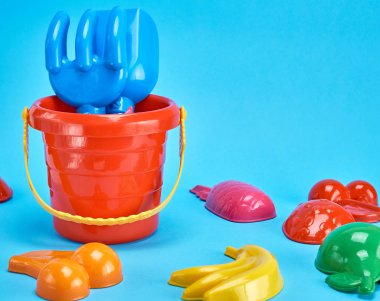 bebek plastiği, kırmızı kova ve mavi arka planda çalınacak diğer eşyalar