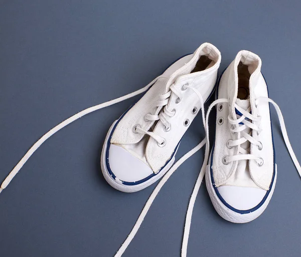 Пара белых старых текстильных кроссовок с развязанными шнурками — стоковое фото
