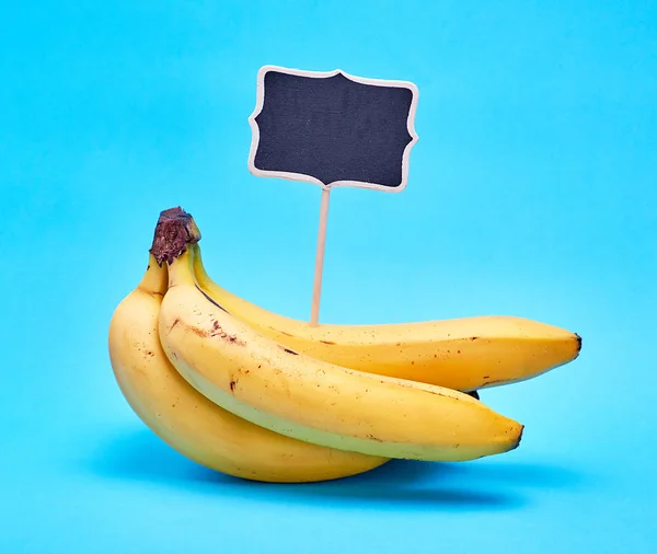 Bunch of ripe yellow bananas and wooden signpost — Stock Photo, Image
