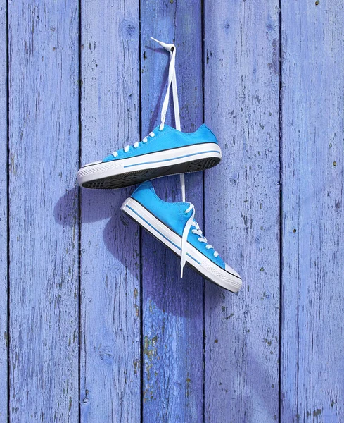 Pair of blue textile sneakers hanging on a nail — Stock Photo, Image