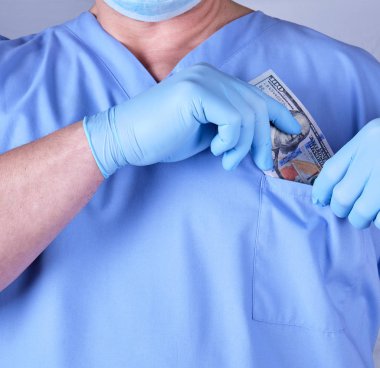 erkek doktor bir tomar dolar gömlek cebine koyar.