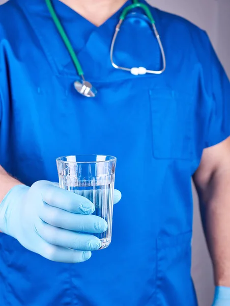 물 한 잔을 들고 파란색 유니폼과 라텍스 장갑에 의사 — 스톡 사진