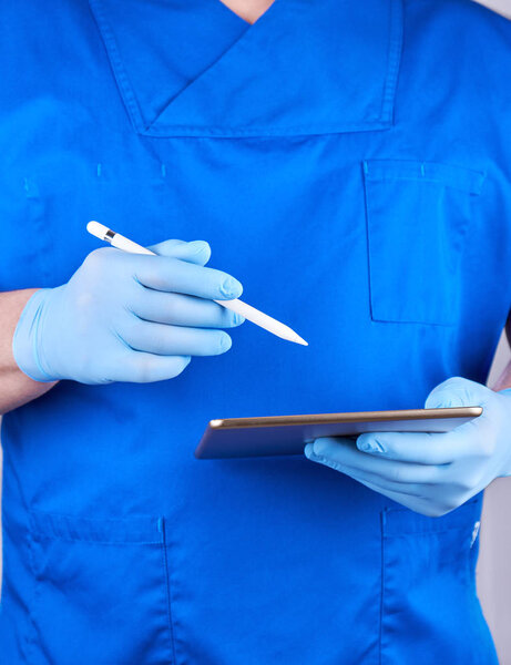 doctor in blue uniform and latex gloves holding an electronic ta