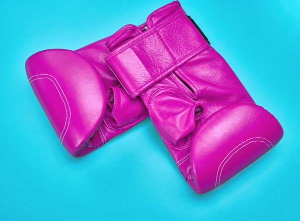 蓝色背景上的一对粉红色皮革拳击手套 — 图库照片