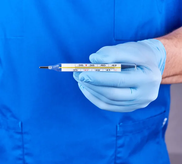 Läkare med blå latex handskar och uniform håller ett glas mercur — Stockfoto