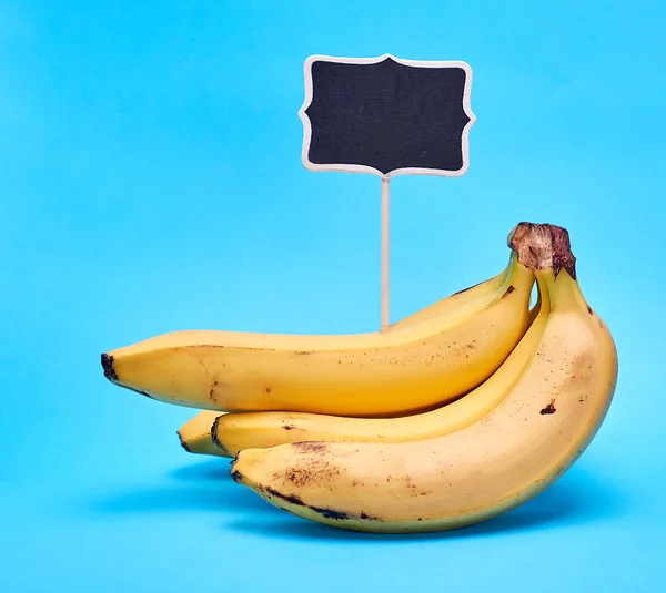 Ripe yellow bananas and wooden signpost with empty black space — Stock Photo, Image