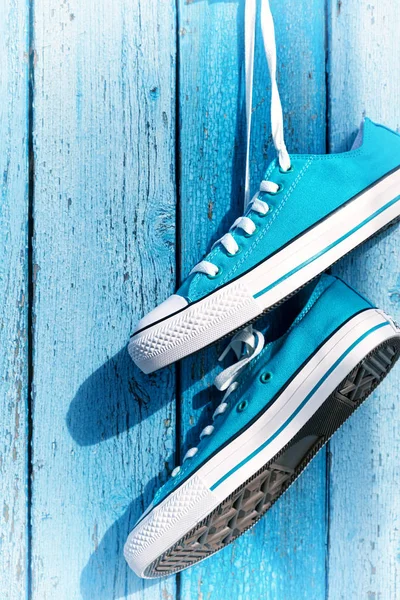 Пара синих текстильных кроссовок висит на гвозде — стоковое фото