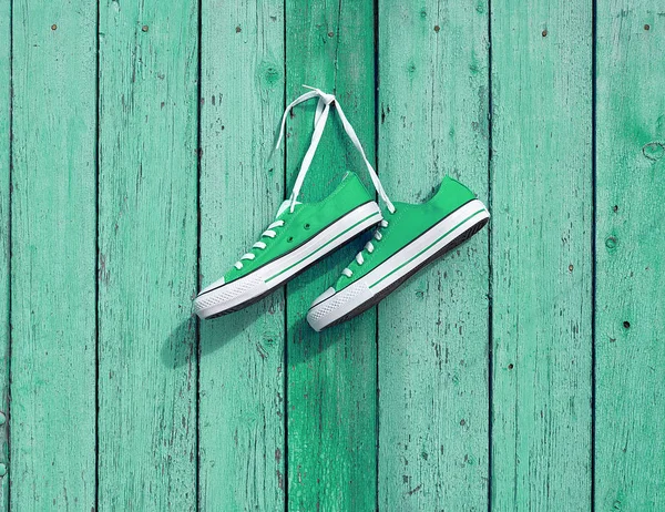 Paio di scarpe da ginnastica in tessuto verde appese a un chiodo sulla parete — Foto Stock