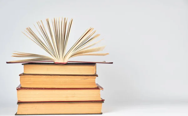 Pila de libros y un libro abierto con páginas amarillas — Foto de Stock