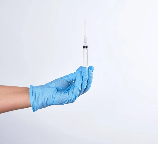 Hand i en blå steril handske håller en plastspruta — Stockfoto