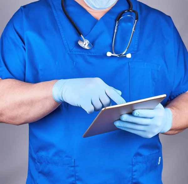 Arzt in blauer Uniform und sterilen Latex-Handschuhen hält einen Auserwählten — Stockfoto