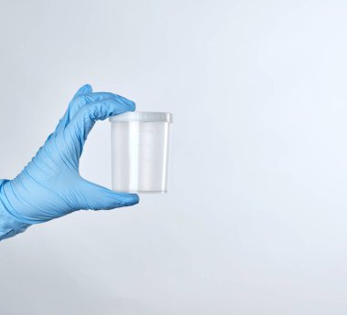 boş bir plastik konteyner için mavi bir steril eldiven elinde tutan