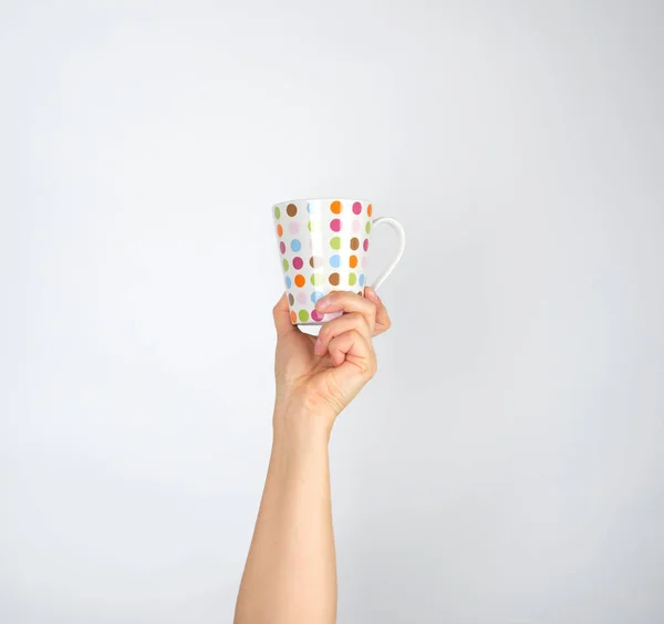 Taza de cerámica con círculos multicolores en una mano femenina en un whi — Foto de Stock