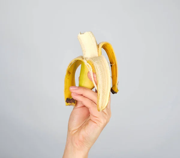 Peeled fresh banana in a female hand on a white background — Stock Photo, Image