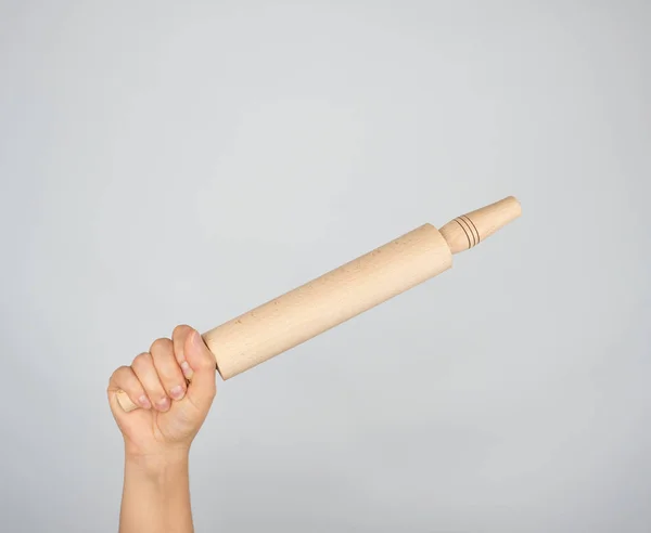 Mão segurando um rolo de madeira — Fotografia de Stock