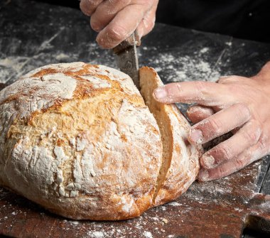 erkek elleri bir bıçak yuvarlak pişmiş ekmek kesti